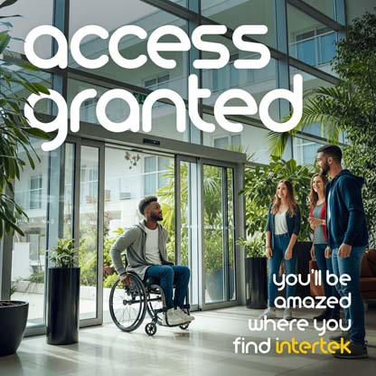A man entering a building in his wheelchair as a group of friends greet him from within
