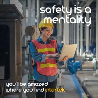 A woman wearing protective equipment while looking at a tablet in an industrial setting