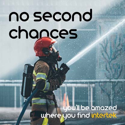 A firefighter in full PPE holding a hose spraying water